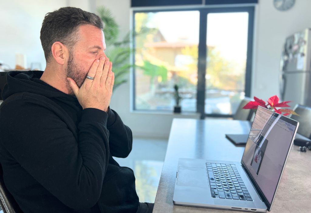 Upset nick looking at traffic on blog on laptop at table