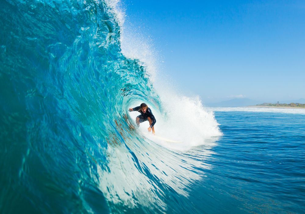 A surfer on a blue ocean wave in the tube got barreled.