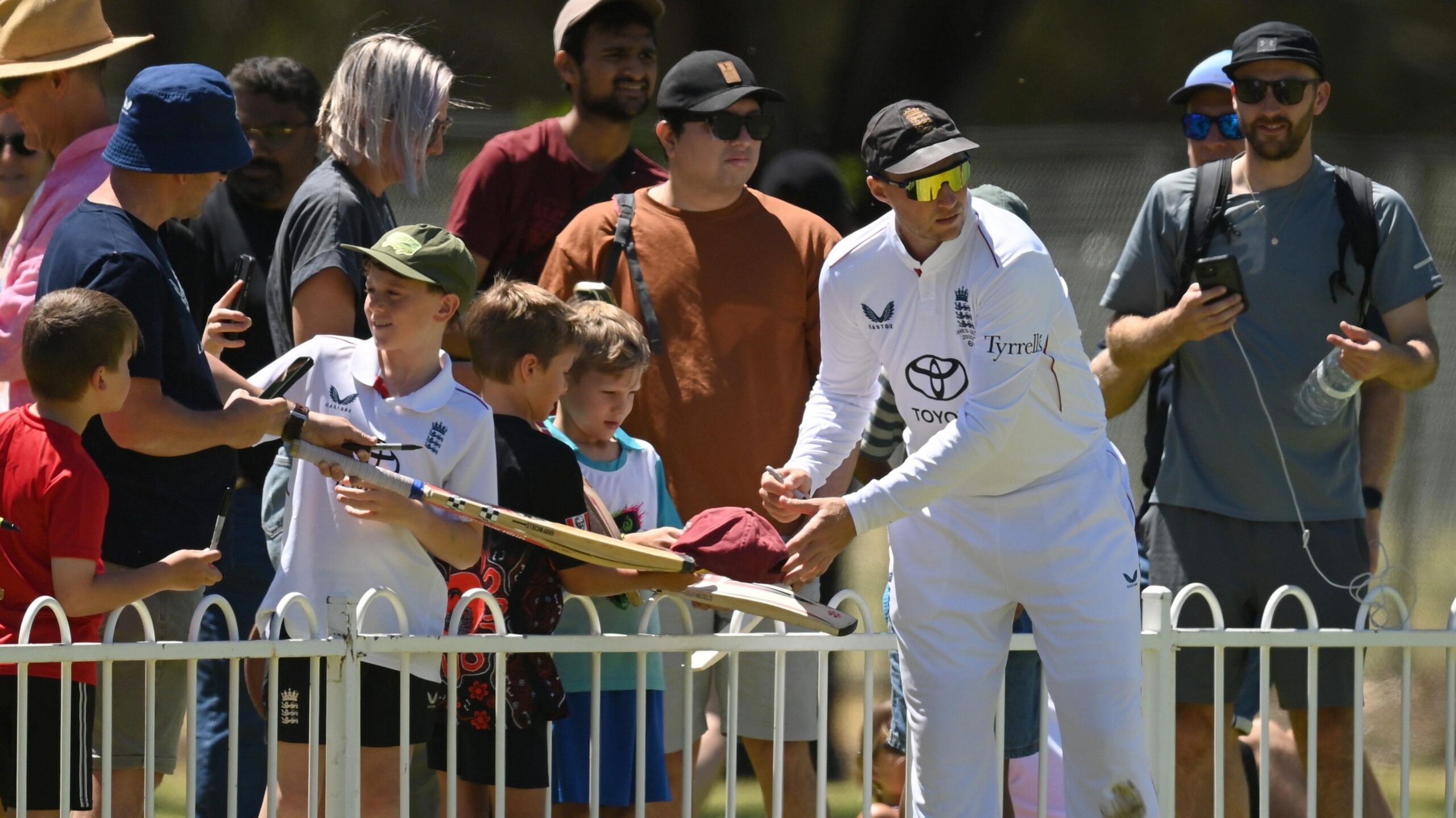 Joe Root signs an autograph on the boundary
