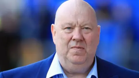 PA Media Former mayor of Liverpool Joe Anderson, who has a bald head and is wearing a surge blue suit jacket and a light blue shirt. He is staring directly at the camera.