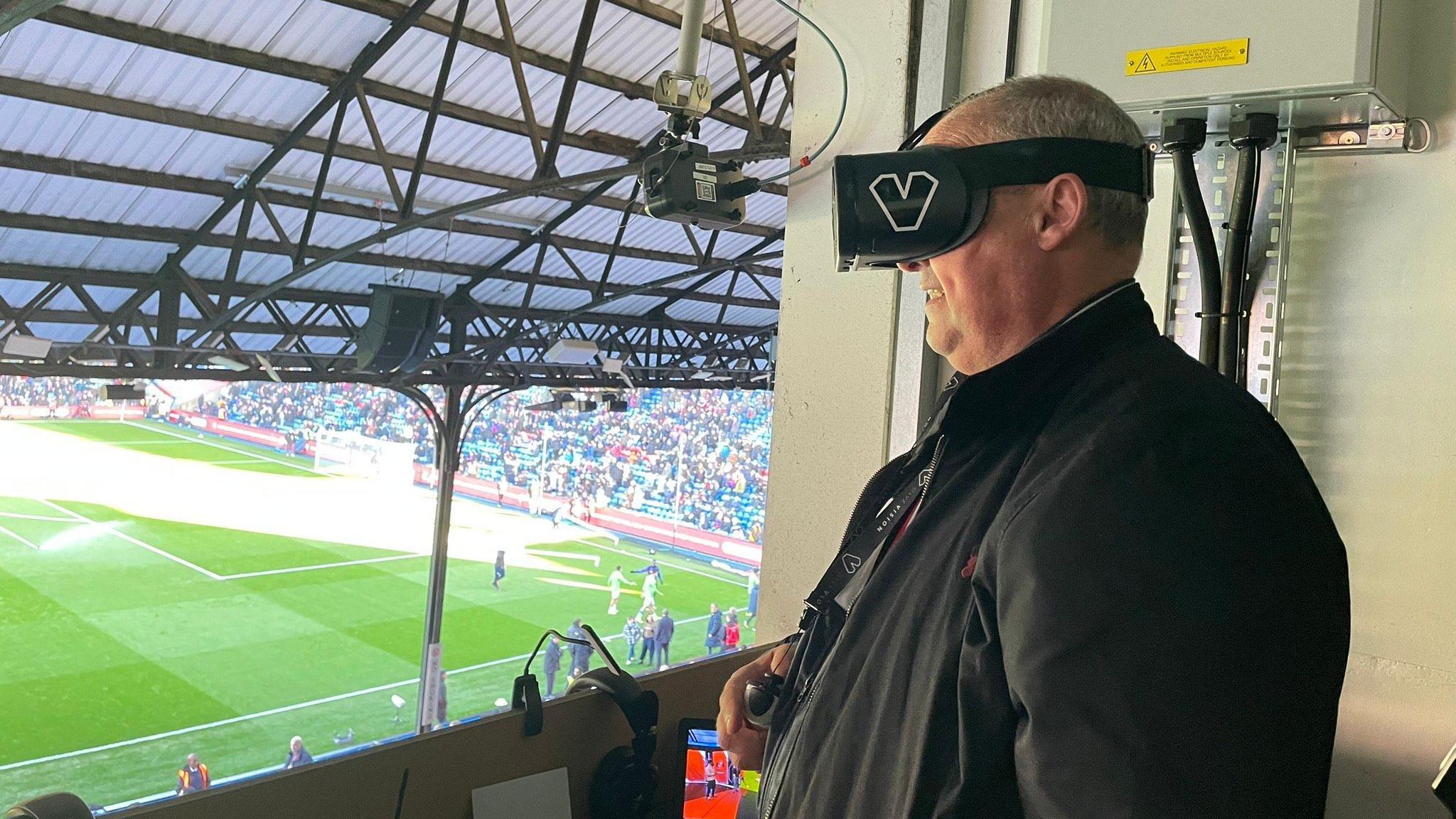 Neale Ormston wearing the GiveVision headset whilst overlooking Selhurst Park from the commentary box