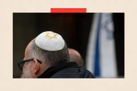 NurPhoto via Getty Images Man wearing a white and gold Kippah