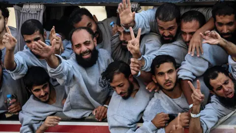 Reuters Former Palestinian detainees, released by Israel in exchange for living Israeli hostages held by Hamas, gesture from a coach, in Khan Younis, southern Gaza (13 October 2025)