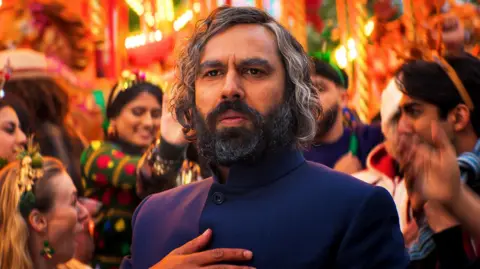 True Brit Entertainment Kunal Nayyar as a contemporary Scrooge, called Mr Sood, in a scene from Christmas Karma