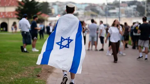 Getty Images A boy wearing a kippah and draped in an Israeli flag walks in Bondi