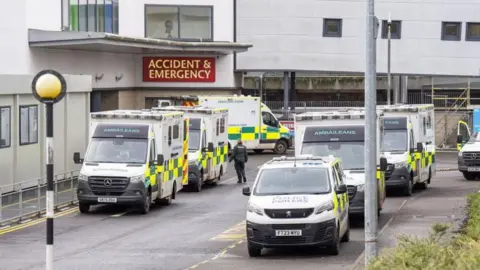 PA Media The Victoria hospital in Kirkcaldy - a large building with an Accident and Emergency sign, and several ambulances parked outside.