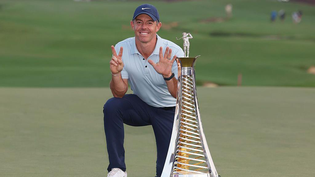 Rory McIlroy holds seven fingers to the camera, alongside the Race to Dubai trophy, after his seventh title