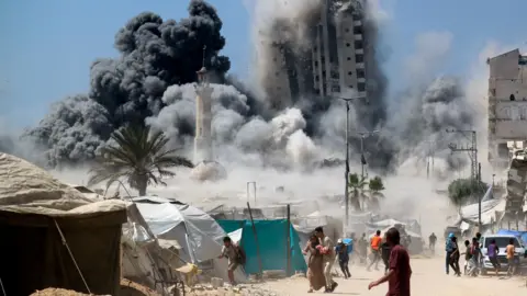 Reuters Palestinians run as a building is destroyed in an Israeli air strike, in Gaza City, northern Gaza (5 September 2025)
