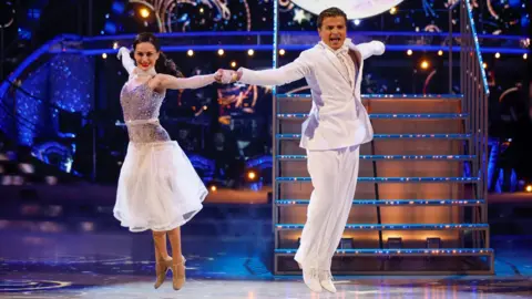 Amber Davies and Nikita Kuzmin in white outfits performing on Strictly