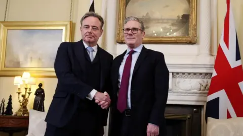 EPA/Shutterstock Belgian Prime Minister Bart De Wever, on the left in a dark three-piece suit visits 10 Downing Street and shakes hands with Sir Keir Starmer, wearing a maroon tie