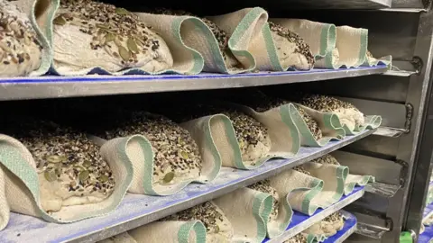Seeded loaves stacked on racks and separated by fabric.