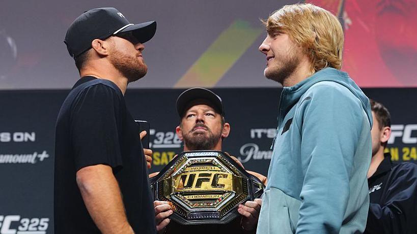 Justin Gaethje faces off with Paddy Pimblett with the UFC belt in between them