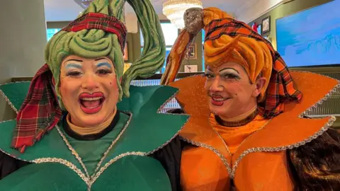 The "cheap and cheerful" Aldianna and Lidleena, Cinderella's sisters, are played by Sam Rabone and Matt Daines are in full costume which consists of . They are wearing green and orange costumes with bright makeup.