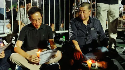 Getty Images Lai (on the right), in a black shirt, was sitting on the ground behind a lit candle during the 2015 vigil commemorating the 1989 Tiananmen Square crackdown