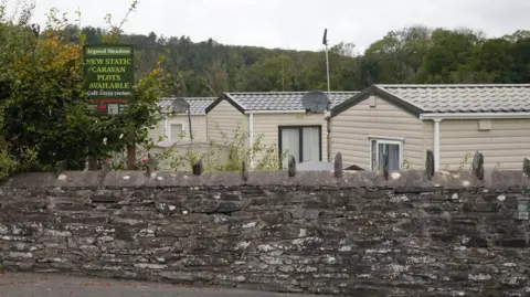 Static caravans at Cenarth caravan park near Newcastle Emlyn, Carmarthenshire, behind a stone boundary wall
