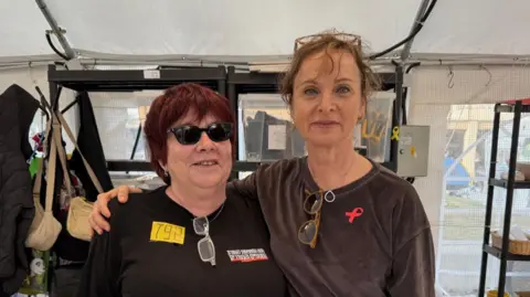 Tali (left) standing next to a fellow volunteer at the Hostages and Missing Families Forum tent at Hostages Square, in Tel Aviv, Israel