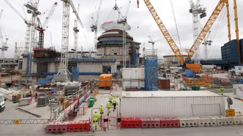 Getty Images A constructions site with a number of cranes and workers in high visibility clothing.