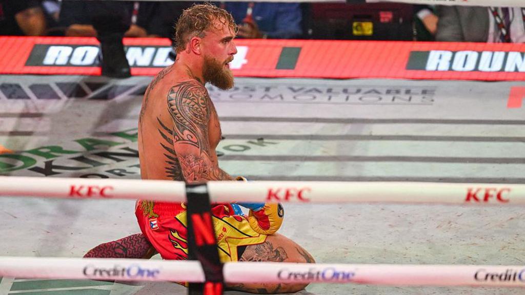 Jake Paul kneels in a boxing ring