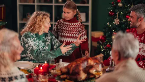 Getty Images A child bargains with her mother over Christmas dinner as family look on