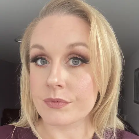 Victoria Woollaston A woman with blonde hair and lipstick on poses for a selfie