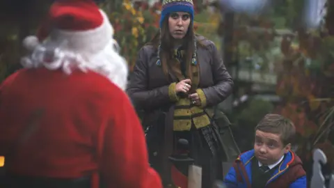 Channel 4 Lenny Rush and Ele McKenzie with a figure dressed as Father Christmas
