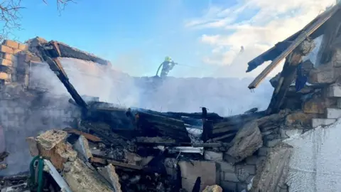 State Emergency Service Of Ukraine A firefighter works at the site of a Russian missile and drone strike in Odesa. Smoke can be seen rising from the debris